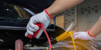 Mężczyzna podłącza akumulator samochodowy do ładowania